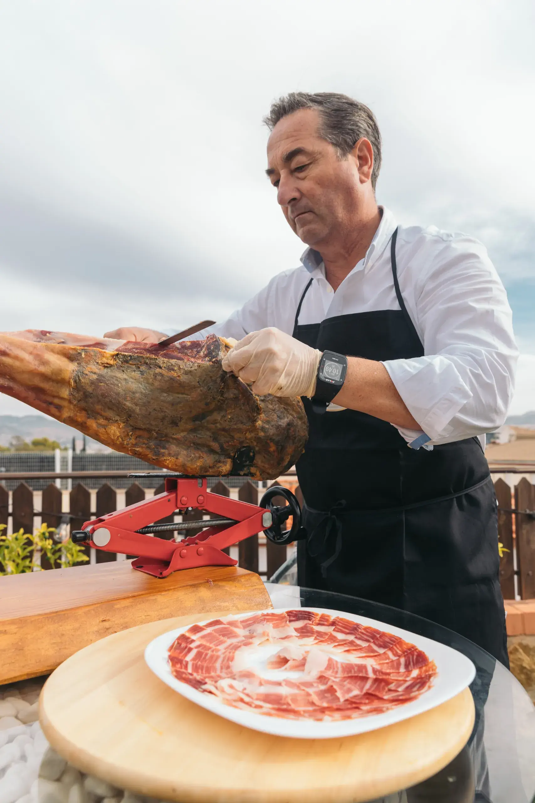 El creador corta el jamón con un plato lleno de lonchas delante