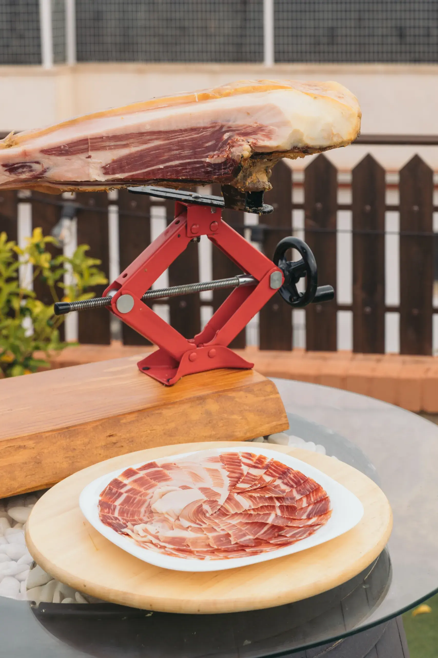 Jamón colocado en horizontal sobre el jamonero, con un plato de jamón cortado delante